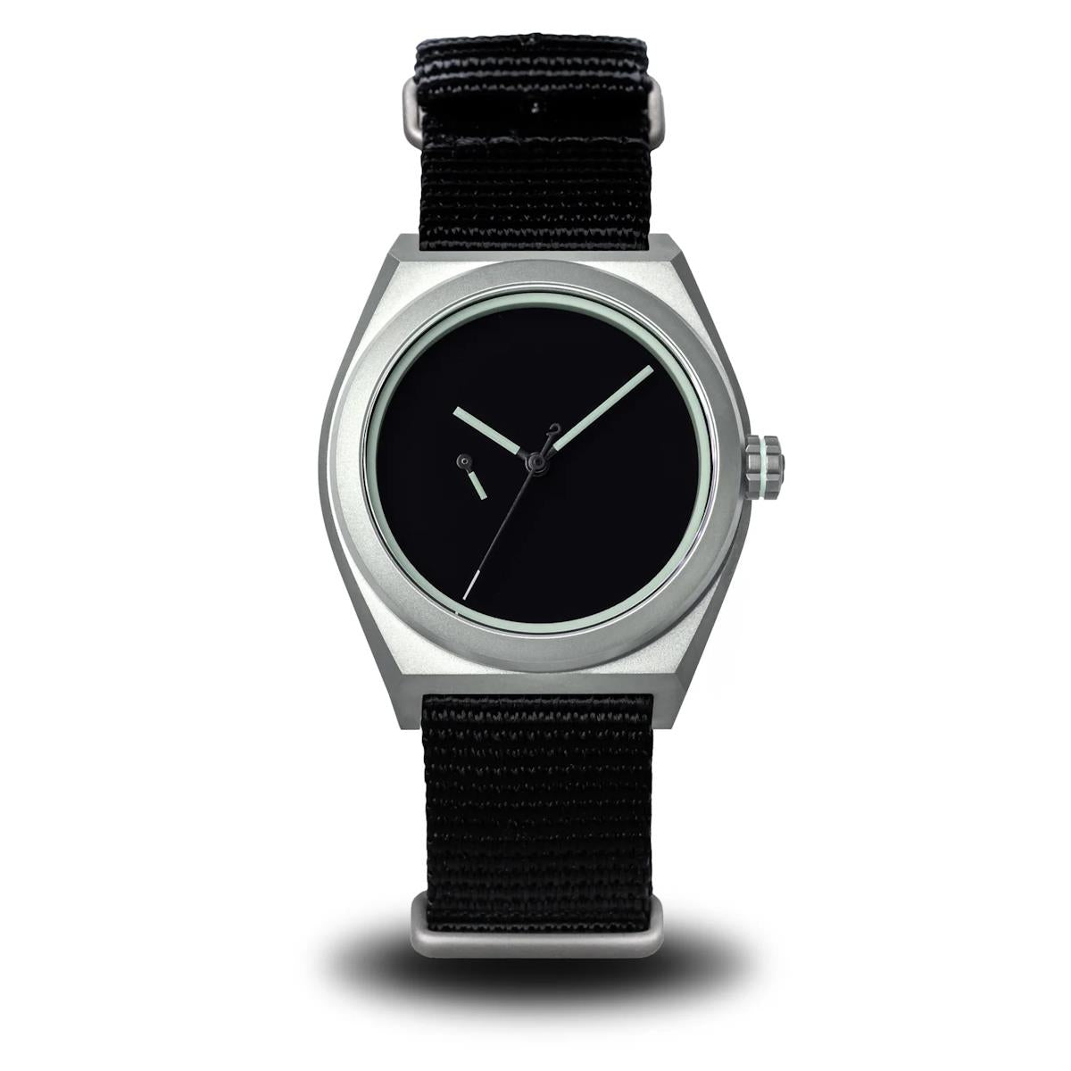 A minimalist wristwatch with a silver-toned metal case, black dial, and black woven fabric strap, shown against a plain white background. Boldr Venture Umbra